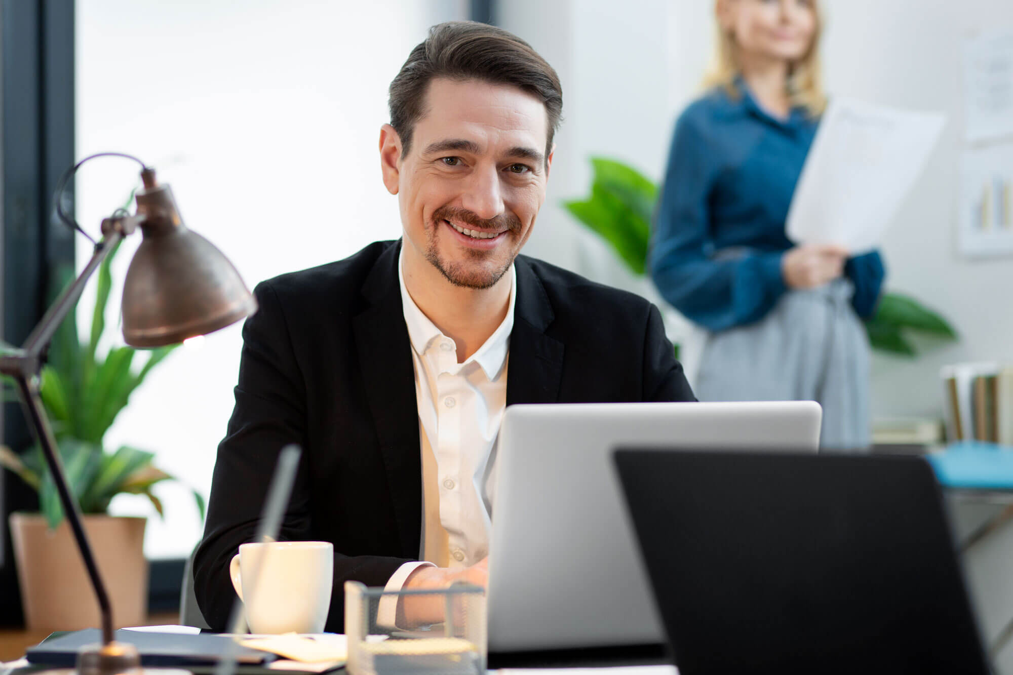 Un employé souriant travaillant sur un ordinateur dans un bureau. Fusion Intérim Limoges propose des missions en CDI pour diverses compétences.