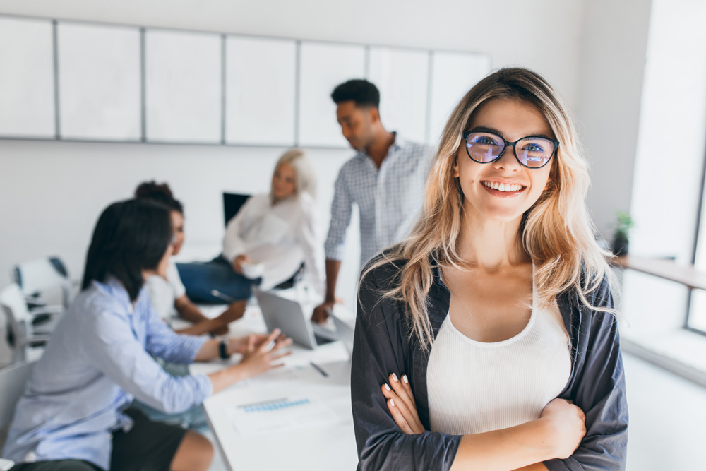 Une jeune femme souriante dans un environnement de bureau moderne. Fusion Intérim Limoges offre des postes dans les services administratifs et professionnels.